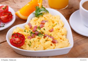 Rührei mit Tomaten und Speck in einer herzförmigen Schüssel: Eier und Speck sind Lebensmittel mit Vitamin B12.