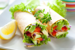 Wraps mit grünem Salat, Tomaten und Käse auf einem Teller angerichtet. Käse ist ein Lebensmittel mit Vitamin B12.
