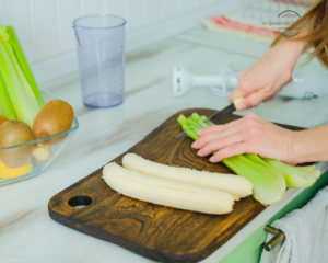 Vitamin B12 und vegane Ernährung. Der Stellenwert von Vitamin B12. Eine Veganerin bereitet einen Smoothie aus Bananen, Kiwi und Sellerie zu.